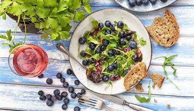 wineglass, blueberries, rosewine, plate, bread, parsley, arugula, salad, crumbs, fork, knife