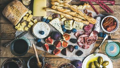 mold, olives, blackberry, blueberry, bread, jamon, cubes, cheese, drink, knife, figs, fork