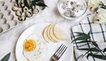 dragonfruit, tablecloth, quaileggs, eggcarton, breakfast, yogurt, pear, plate, friedegg, fork, flowers, bowl
