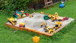 dumptruck, excavator, truck, jeep, backyard, sandbox, toys, pail, lawn, shrub, sand